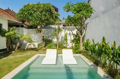 two white chairs sitting next to a swimming pool at Villa Marina Seminyak in Seminyak