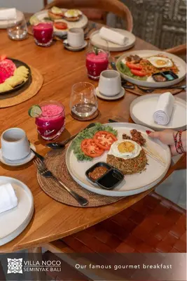 a wooden table with plates of food on it at Noco Luxury Villa Seminyak in Seminyak