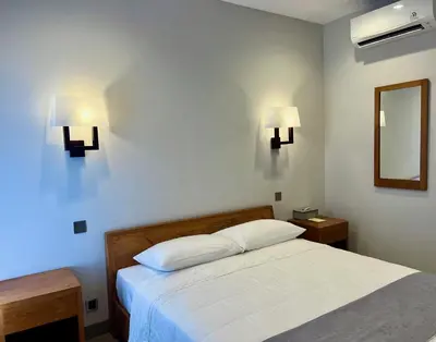a bedroom with a bed and two lights on the wall at Charlie Guest House in Nusa Dua