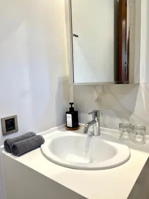 a white bathroom sink with a mirror and a towel at Charlie Guest House in Nusa Dua
