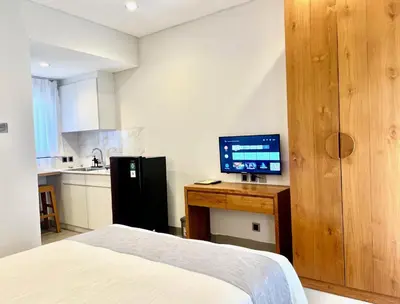 a bedroom with a bed and a desk with a television at Charlie Guest House in Nusa Dua