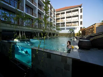 a woman in a swimming pool in a building at Grand Zuri Kuta Bali in Kuta
