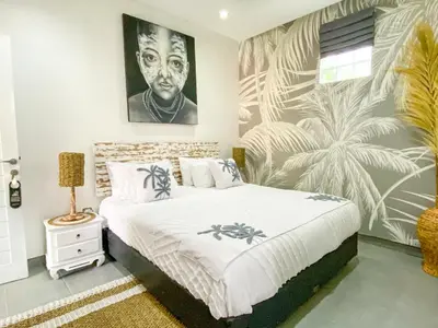 a bedroom with a bed with a painting on the wall at Villa Coco Legian in Legian