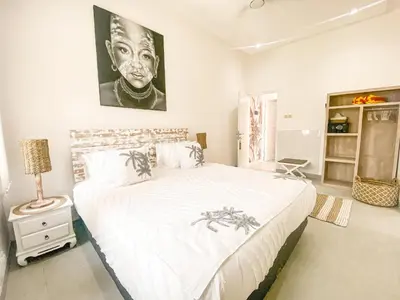 a bedroom with a large white bed with a painting on the wall at Villa Coco Legian in Legian