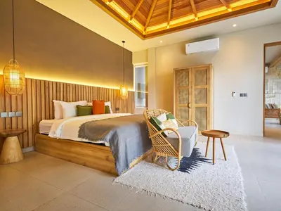 a bedroom with a large bed and a chair at Luna Ola Villa Berawa in Canggu