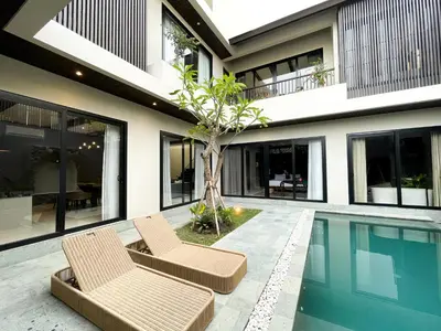 a house with two chairs and a swimming pool at Luna Ola Villa Berawa in Canggu