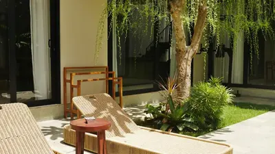 a patio with chairs and a table and a tree at Luna Ola Villa Berawa in Canggu