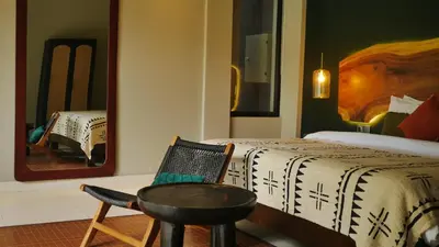 a bedroom with a bed and a chair and a mirror at Luna Ola Villa Berawa in Canggu