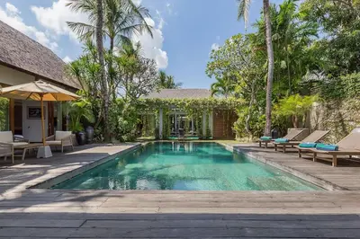 a swimming pool with chairs and a house at Eshara 1 our Tropical & luxury 3BR Villa 450m from beach in Seminyak