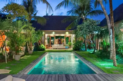 a swimming pool in front of a house with palm trees at Eshara 3 our Peaceful 3BR Pool Villa close to Oberoi Beach in Seminyak