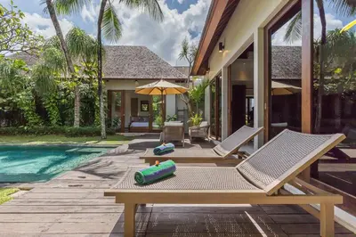 a patio with two lounge chairs and a pool at Eshara 3 our Peaceful 3BR Pool Villa close to Oberoi Beach in Seminyak