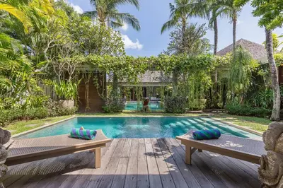 a swimming pool with two benches in front of a house at Eshara 21 our Luxury 5BR Villa Escape and huge pool Oberoi Beach in Seminyak