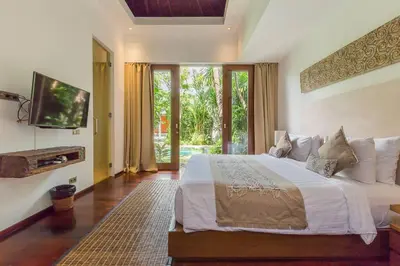 a bedroom with a large bed and a tv at Eshara 23 an Amazing 5 BR Pool Villa walking distance to Beach in Seminyak