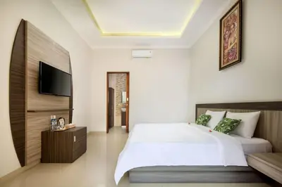 a bedroom with a bed and a tv on the wall at Jineswari Kuta by Kamara in Kuta