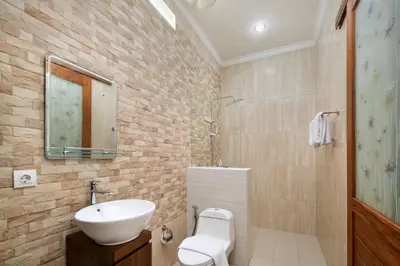 a bathroom with a sink and a toilet and a mirror at Jineswari Kuta by Kamara in Kuta