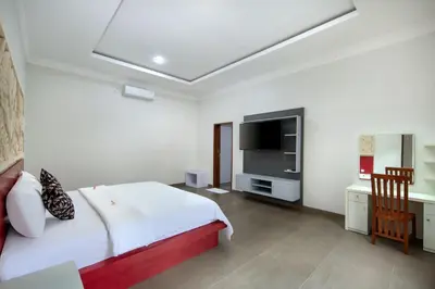 a bedroom with a bed and a television in it at Jineswari Kuta by Kamara in Kuta