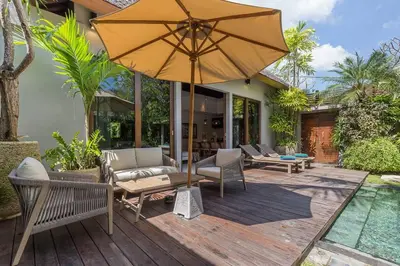 an umbrella sitting on a deck next to a pool at Eshara 123 in Oberoi our 8 BR Villa with 3 Pool close to Beach in Seminyak