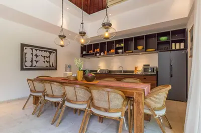 a kitchen with a long wooden table and chairs at Eshara 123 in Oberoi our 8 BR Villa with 3 Pool close to Beach in Seminyak
