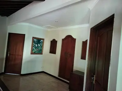 a room with two wooden doors and white walls at Villa Layang Bulan a homey guesthouse for men near the beach in North Kuta in Denpasar