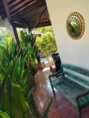a green bench sitting on a patio with plants at Villa Layang Bulan a homey guesthouse for men near the beach in North Kuta in Denpasar