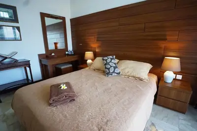 a bedroom with a large bed with a wooden headboard at Guildwood Villa Bali in Sanur