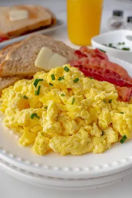 a plate of scrambled eggs and toast on a table at Guildwood Villa Bali in Sanur