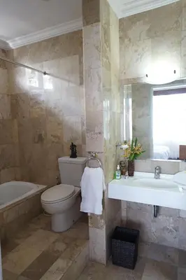 a bathroom with a toilet and a tub and a sink at Guildwood Villa Bali in Sanur