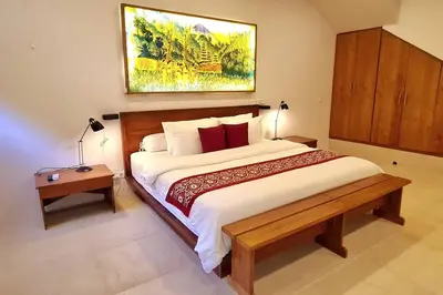 a bedroom with a large bed and a painting on the wall at Jado 1 Unique Cinema Entertainment Villa in Umalas in Kerobokan