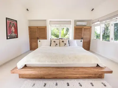 a bedroom with a large bed and windows at Stylish 2bdr poolvilla Centre Seminyak in Seminyak