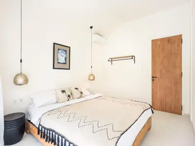 a white bedroom with a bed and a wooden door at Stylish 2bdr poolvilla Centre Seminyak in Seminyak