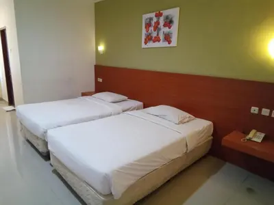 two beds in a hotel room with a phone at Puri Dibia Kuta Hotel & Apartment in Kuta