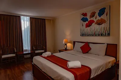 a hotel room with a large bed and a window at Puri Dibia Kuta Hotel & Apartment in Kuta