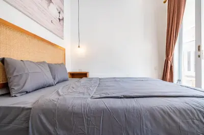 a bedroom with a large bed with gray sheets at Lumturi House - Centrally Located in Seminyak