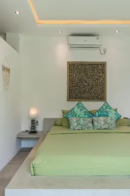 a bedroom with a large bed with a white wall at Villa Cempaka Ungu - Tranquil & Chic Pool 4-Bedroom Villa In The Heart Of Seminyak in Seminyak