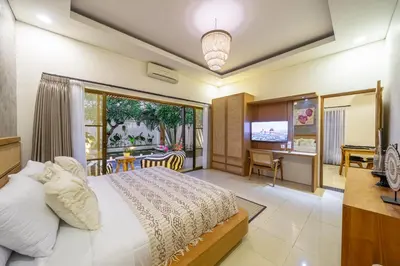 a bedroom with a bed and a desk and a television at Kalya Villa by RPM in Seminyak