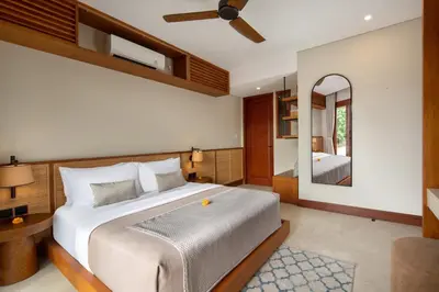 a bedroom with a large bed and a mirror at Kolila Villa Seminyak by Ini Vie Hospitality in Seminyak