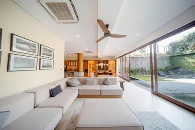 a living room with white furniture and a large window at Kolila Villa Seminyak by Ini Vie Hospitality in Seminyak