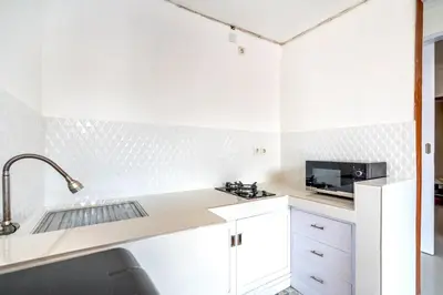 a white kitchen with a sink and a microwave at Lumturi House - Centrally Located in Kerobokan