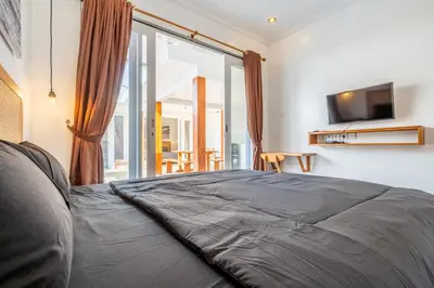 a bedroom with a large bed with a television on the wall at Lumturi House - Centrally Located in Kerobokan