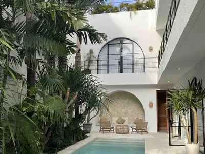 a house with a swimming pool in a courtyard with palm trees at Villa Anwa Cove - Gorgeous 6-BR & 2-Pool Villa in Bali in Umalas