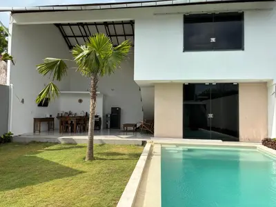 a villa with a swimming pool in front of a house at Villa Lina, Nusa Dua Benoa in Nusa Dua