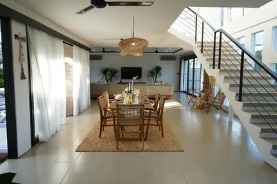 a dining room with a table and chairs and a staircase at Admire Villa - a luxury private villa with Pool in Legian