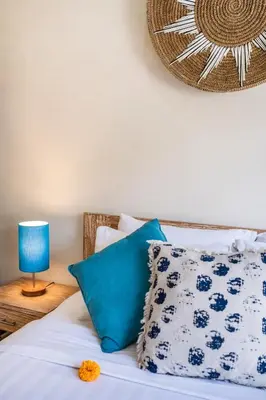 a bed with blue and white pillows and a blue lamp at Villa Sebelas Legian in Seminyak