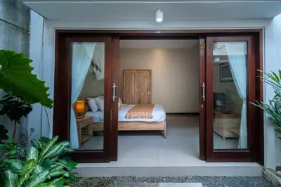 a bedroom with a bed and sliding glass doors at Villa Sebelas Legian in Seminyak