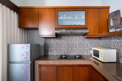 a small kitchen with wooden cabinets and a refrigerator at Villa Sebelas Legian in Seminyak