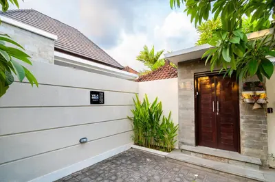 a house with a wooden door and trees at Villa Sebelas Legian in Seminyak