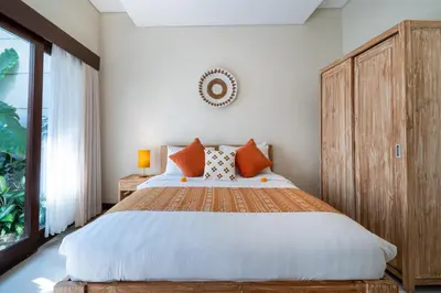 a bedroom with a large bed and a large window at Villa Sebelas Legian in Seminyak