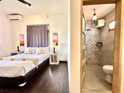 a bedroom with a large bed and a bathroom at Casa Sessy Legian in Seminyak