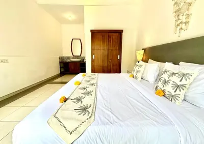 a bedroom with a large white bed with flowers on it at Casa Sessy Legian in Seminyak
