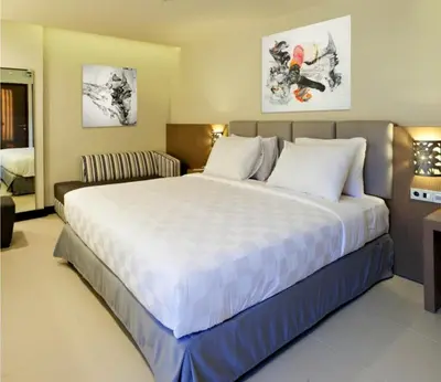 a bedroom with a large bed and a couch at Euphoria Hotel in Legian